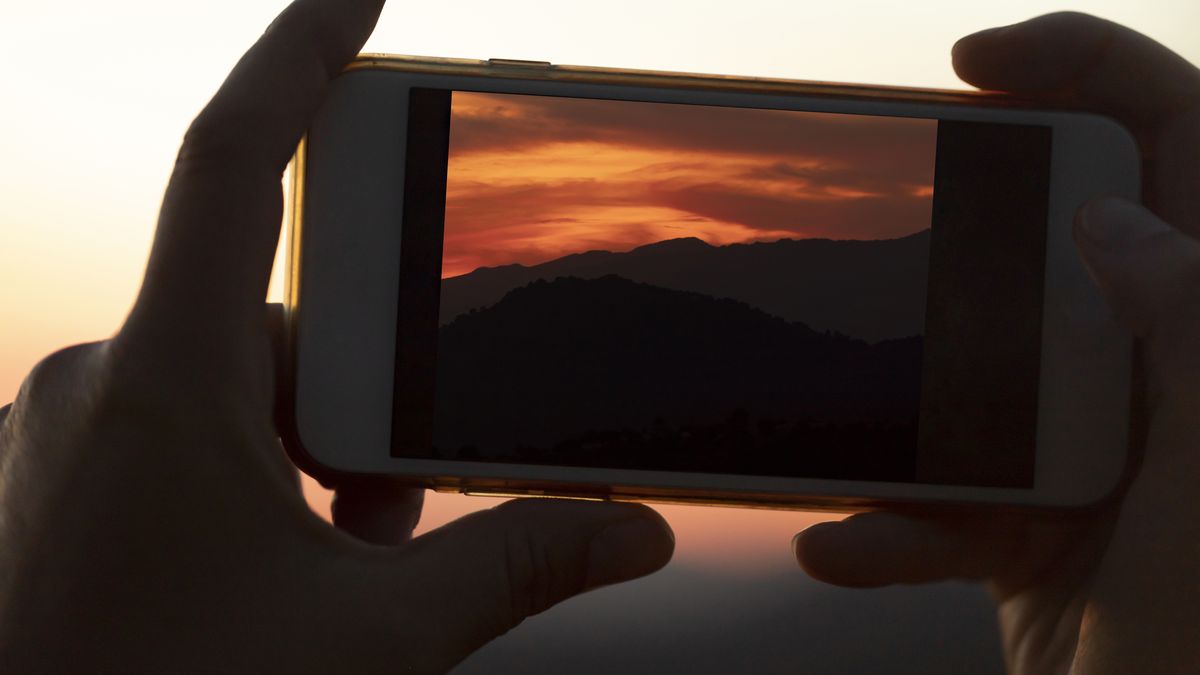 Hands holding iPhone scrolling through photo gallery searching for duplicate photos